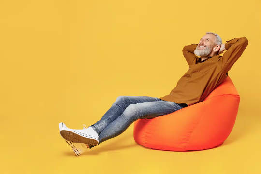 a man sitting  back on a bean bag chair with his hands behind his head